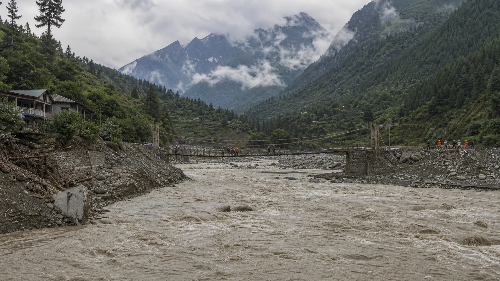 Valle montañoso con un río crecido y equipos de rescate a distancia