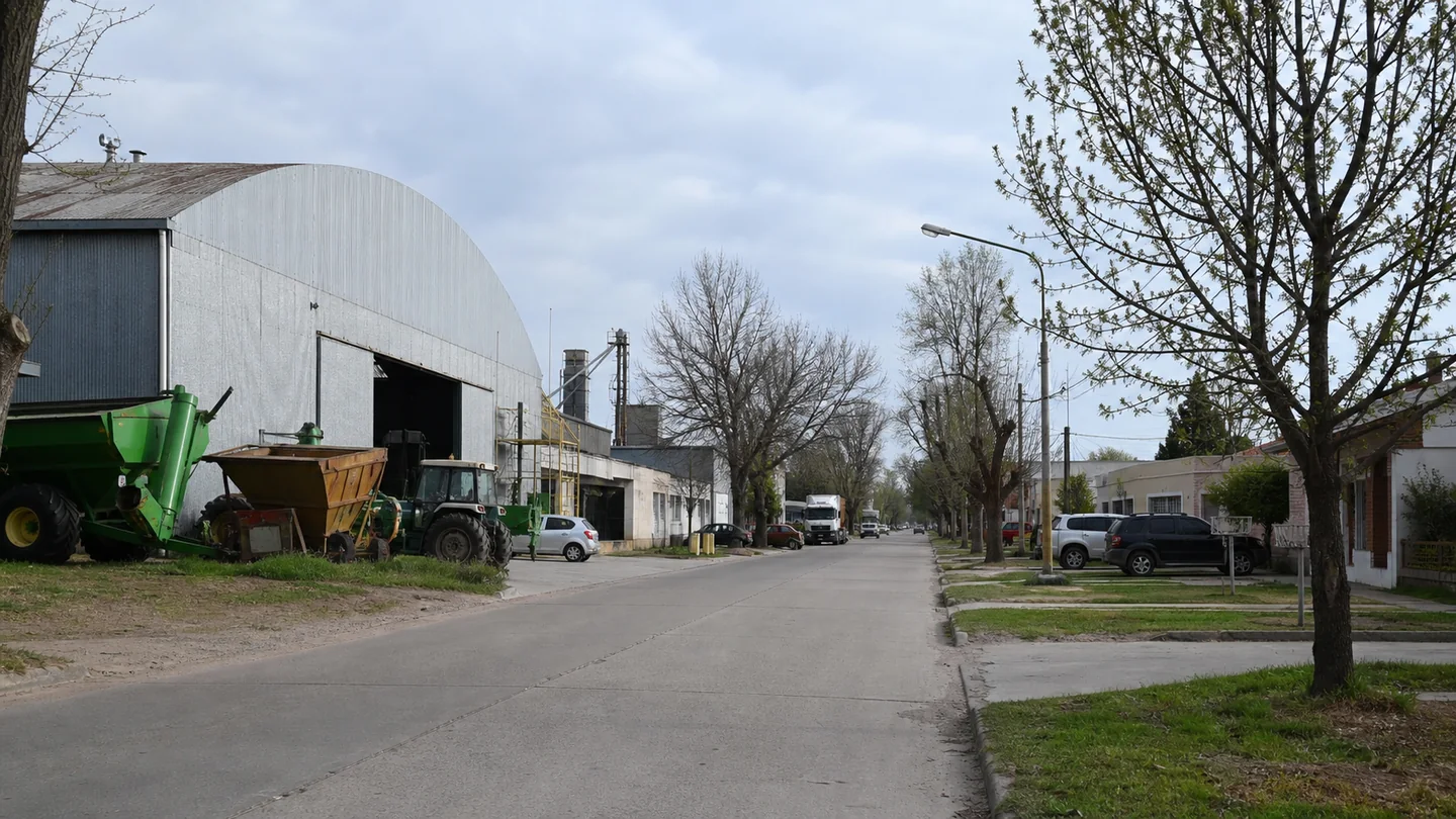 Galpón, maquinaria agrícola y viviendas junto a una calle de una ciudad intermedia