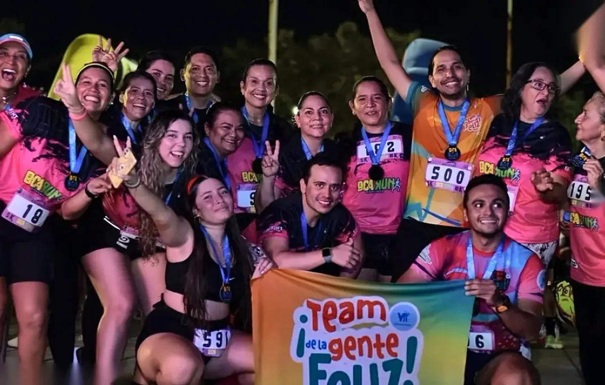 Grupos de running y familias celebrando juntos con pancartas y medallas en la llegada de Night Run Neon