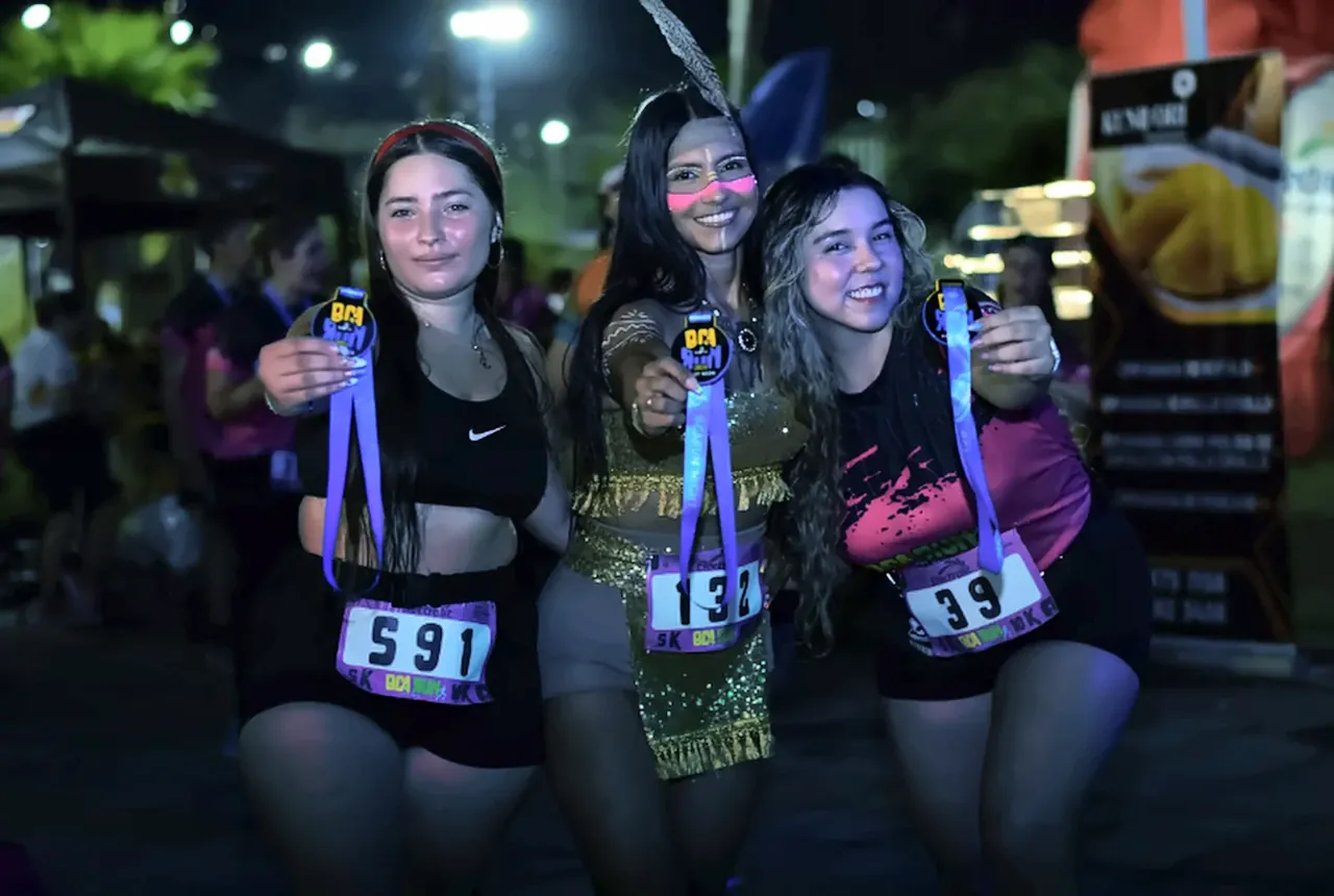 Corredoras exhibiendo las medallas oficiales de Night Run Neon con detalles fluorescentes y tocados temáticos