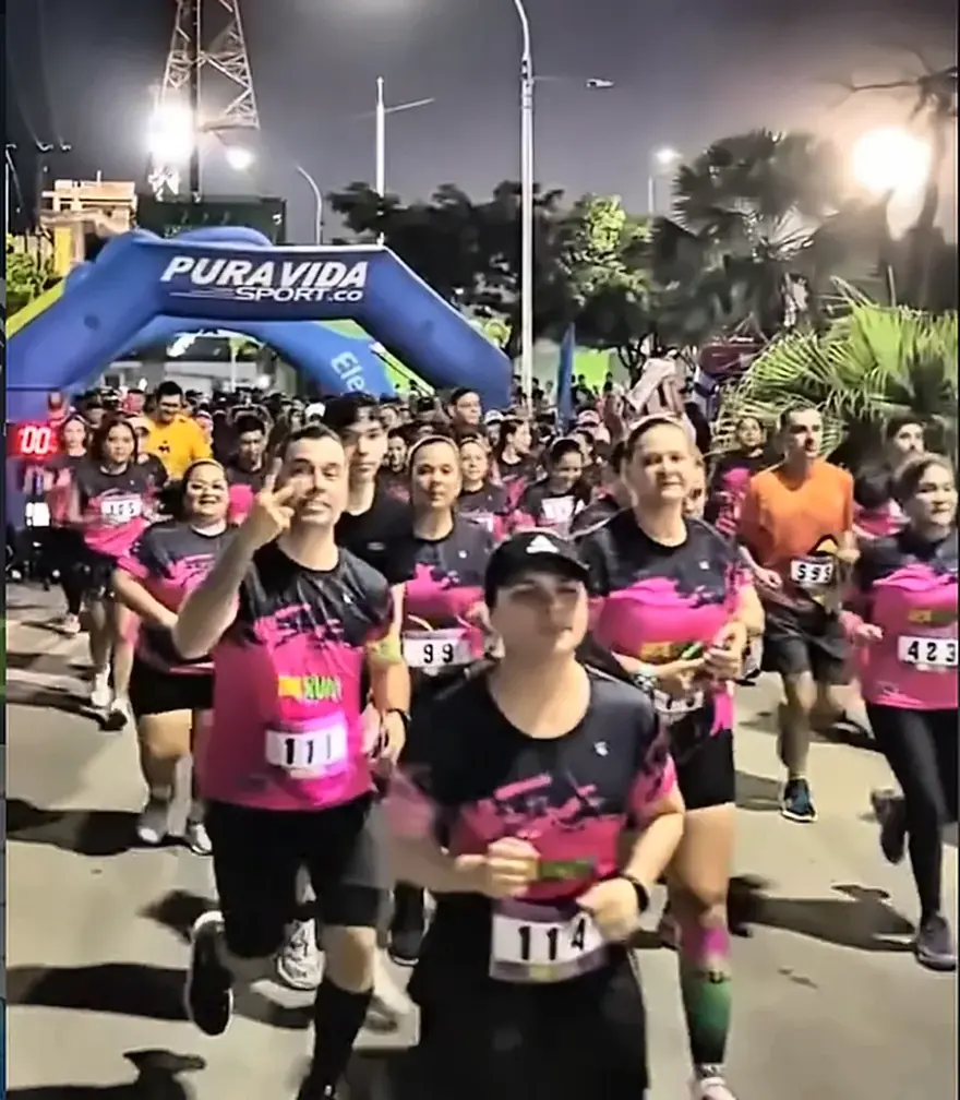 Pelotón de corredores largando en la noche de Barrancabermeja bajo el arco de meta en Night Run Neon