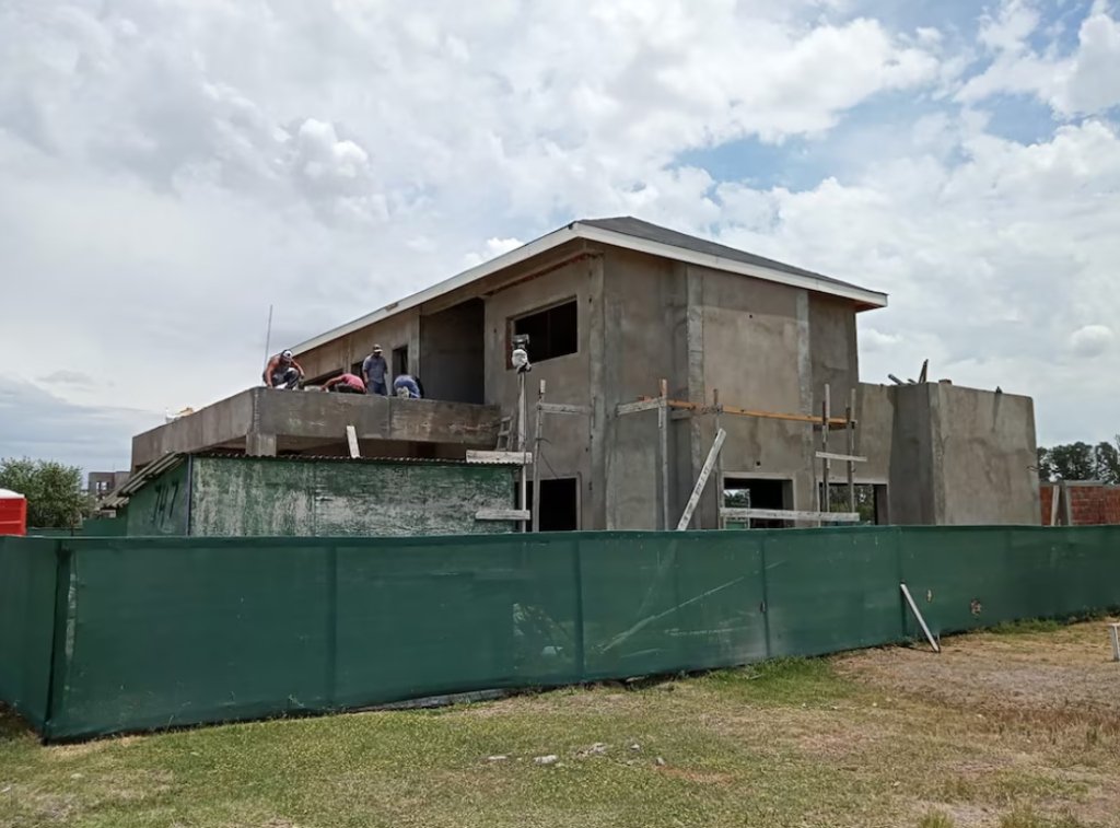 Vista aérea de una vivienda moderna en construcción junto a un espejo de agua, en una urbanización del corredor norte bonaerense