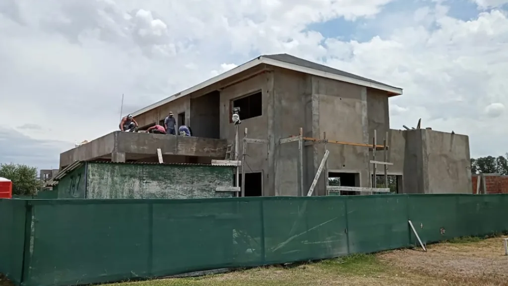 Vista aérea de una vivienda moderna en construcción junto a un espejo de agua, en una urbanización del corredor norte bonaerense