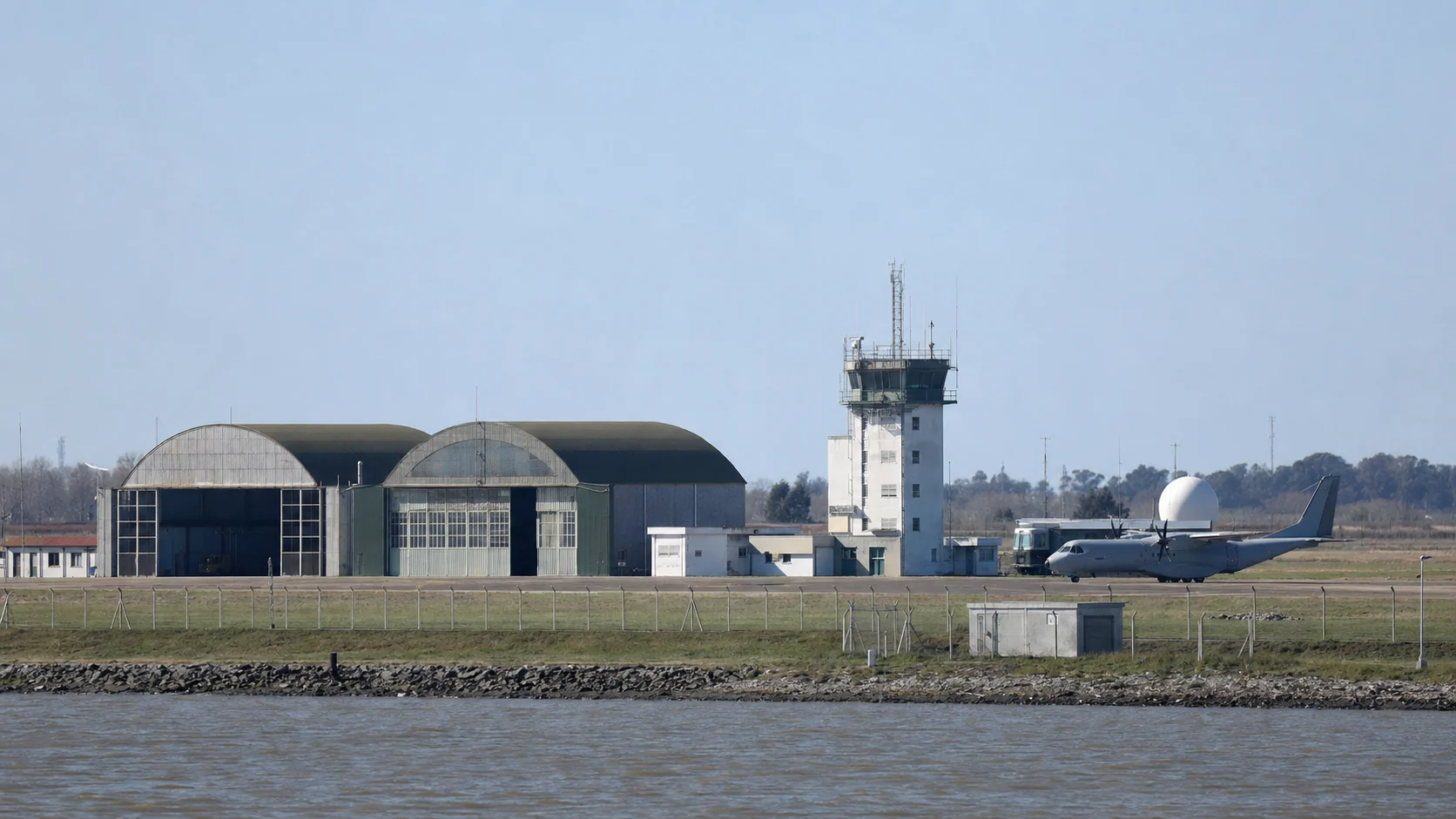 Pista de una base aeronaval argentina con hangares y aviones a distancia