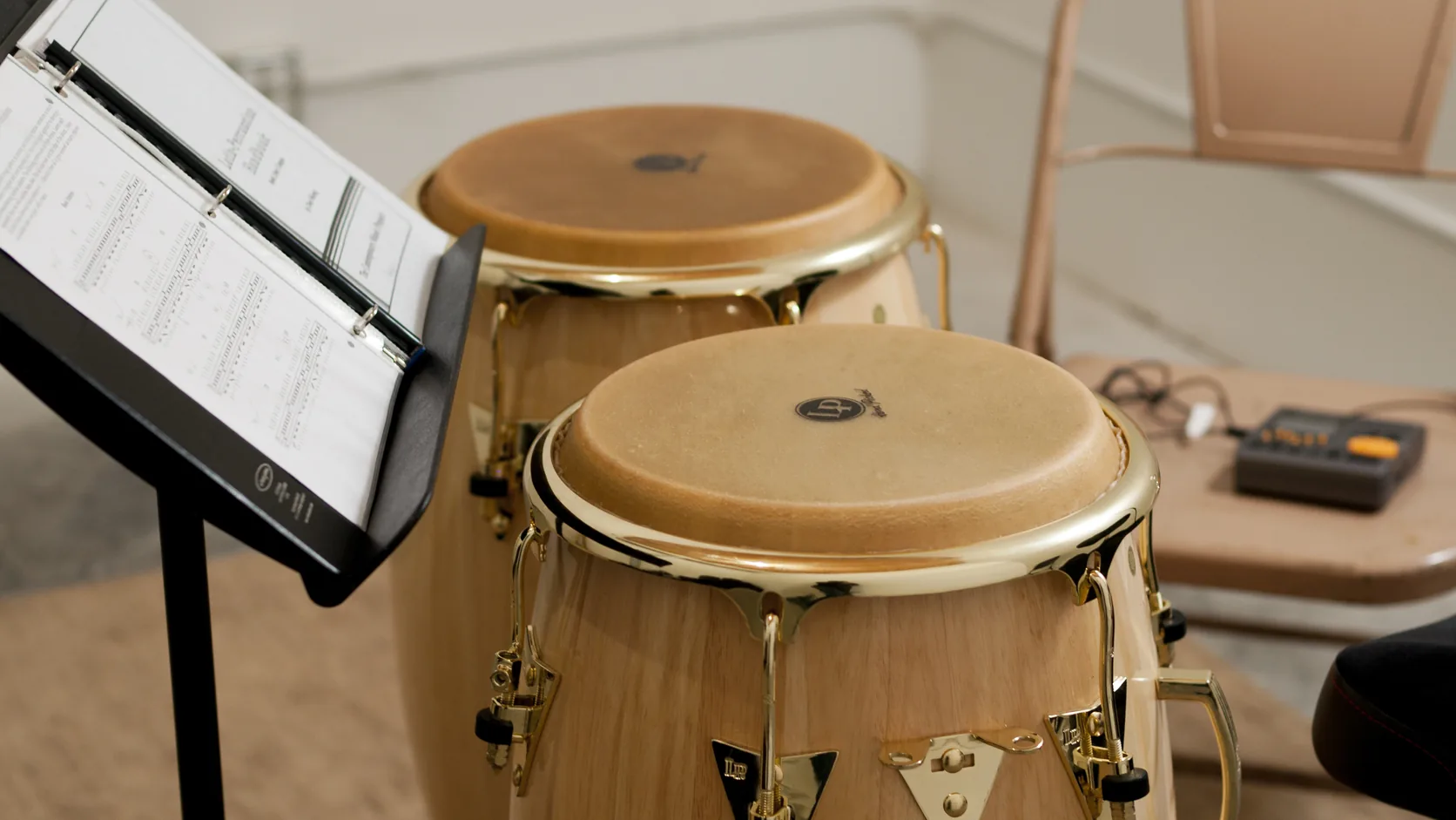 Set de tumbadoras y percusión sobre un escenario de recital iluminado con reflectores cálidos